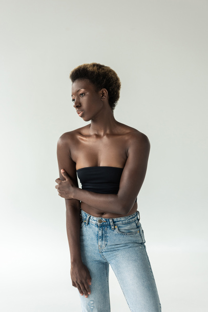 beautiful african american girl in jeans and black top isolated on grey - Foto, imagen