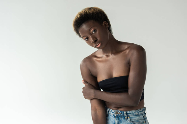 ελκυστική Αφροαμερικάνα με τζιν και μαύρο μπλουζάκι που απομονώνεται σε γκρι - Φωτογραφία, εικόνα