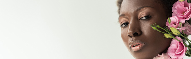 обличчя афроамериканки з рожевими квітами еустоми ізольовано на сірому, панорамному знімку
 - Фото, зображення