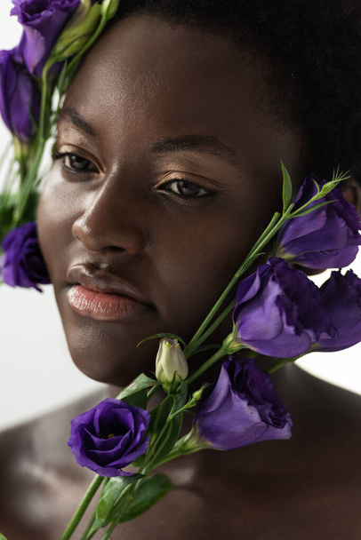 beautiful nude african american woman with purple eustoma flowers isolated on white - Φωτογραφία, εικόνα