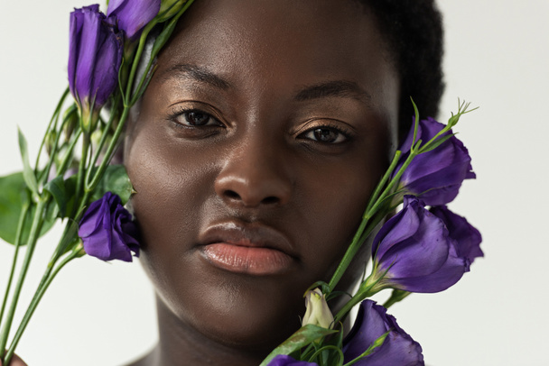 attractive african american woman with purple eustoma flowers isolated on white - Foto, afbeelding