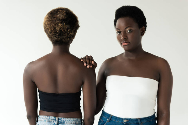 atraktivní africké americké přátele v džínách a topy stojící izolované na šedé  - Fotografie, Obrázek