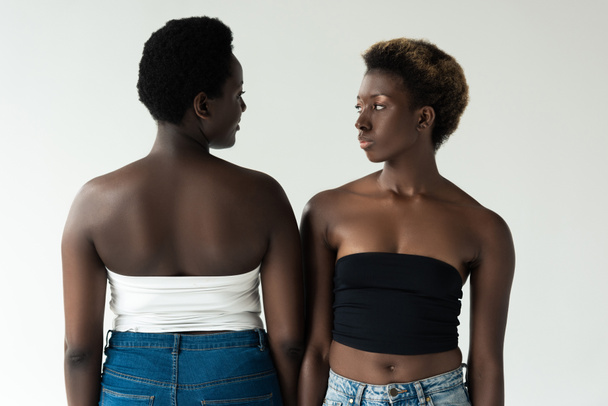 Африканские американские девушки в джинсах и топах, стоящие изолированные на серой
  - Фото, изображение