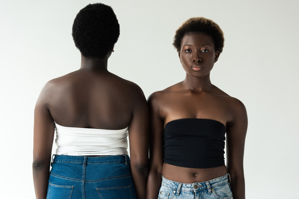mujeres afroamericanas en jeans y tops de pie aisladas en gris
  - Foto, Imagen