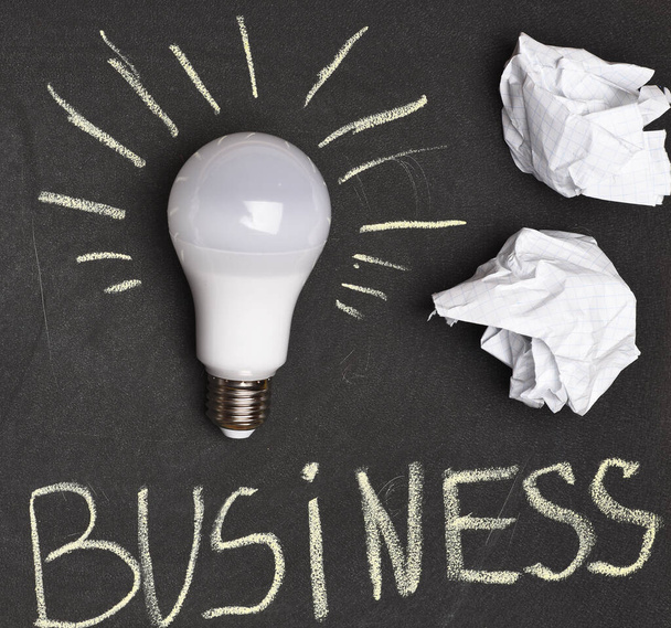 Business idee lamp met verkreukeld papier op grijze boord achtergrond - Foto, afbeelding