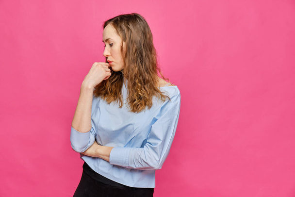 Stylish caucasian girl in a pale blue t-shirt looks away thoughtfully on a pink background. Close up. - Fotoğraf, Görsel