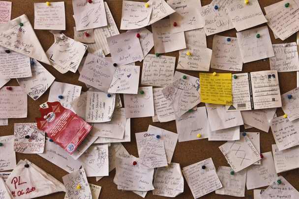 Post-it-Zettel klebten chaotisch an der Wand - hektisches Konzept. in verschiedenen Sprachen des Wortes - Foto, Bild