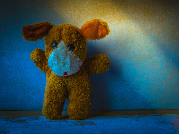 Děsivé dítě ve tmě. Malá hračka osamělého psa v tmavomodré místnosti s pruhem světla. Pojmy dětská psychologie, strach nebo bezesná noc. - Fotografie, Obrázek