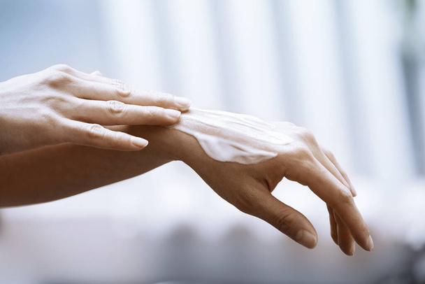 Woman applying moisturizing cream on hands - Foto, imagen