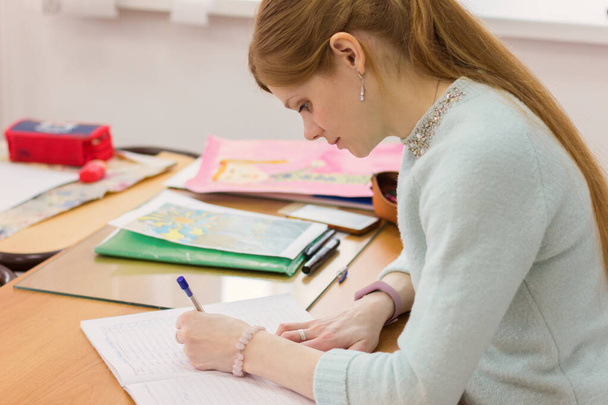 jeune belle femme écrivant avec la main gauche. gaucher rousse femme aux cheveux. enseignant en classe
. - Photo, image