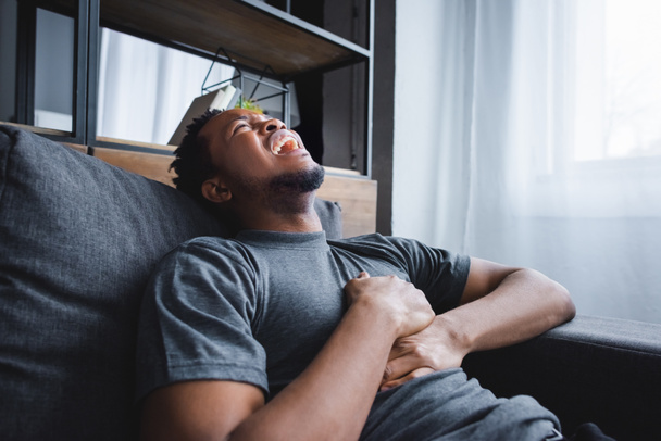 stressed african american man having heart attack at home - Valokuva, kuva