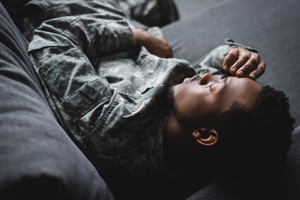 tired african american soldier in military uniform sleeping in sofa at home - Фото, зображення