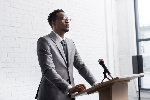 pewny siebie afrykański mówca biznesu stoi na podium z mikrofonem w sali konferencyjnej - Zdjęcie, obraz