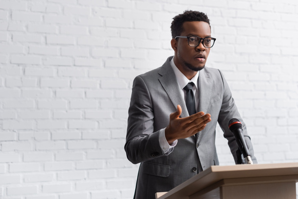 confiante afro-americano orador de negócios na tribuna com microfone na sala de conferências
 - Foto, Imagem