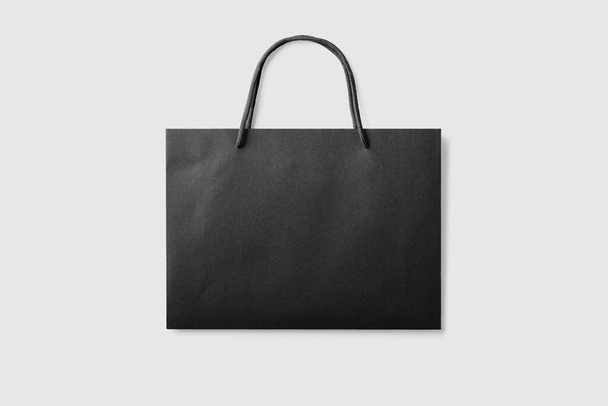 Převzetí prázdné nákupní tašky z černého papíru s držadly na světle šedém pozadí. Vysoké rozlišení. - Fotografie, Obrázek