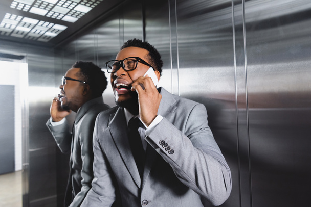 llorando hombre de negocios afroamericano hablando en smartphone y sufriendo de ataque de pánico en ascensor
 - Foto, Imagen