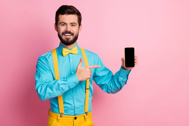 Portrait of his he nice attractive cheerful cheery imposing bearded guy wearing mint blue shirt showing new digital gadget presentation isolated over pastel pink color background - Photo, image
