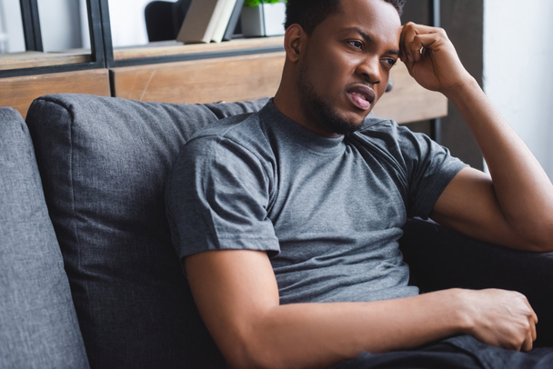 sad african american man with psychology problem sitting on sofa at home - Photo, Image