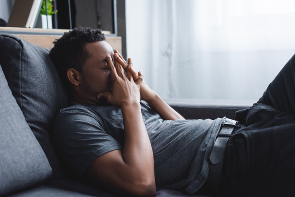 hombre afroamericano estresado sentado en el sofá en casa
 - Foto, Imagen