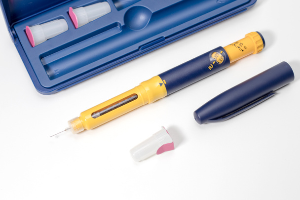 Инсулиновая ручка с каплей инсулина на кончике иглы изолирована на белом фоне. Медицинские приборы используются для самостоятельной инъекции при лечении диабета. Всемирный день диабета и концепция здравоохранения. - Фото, изображение