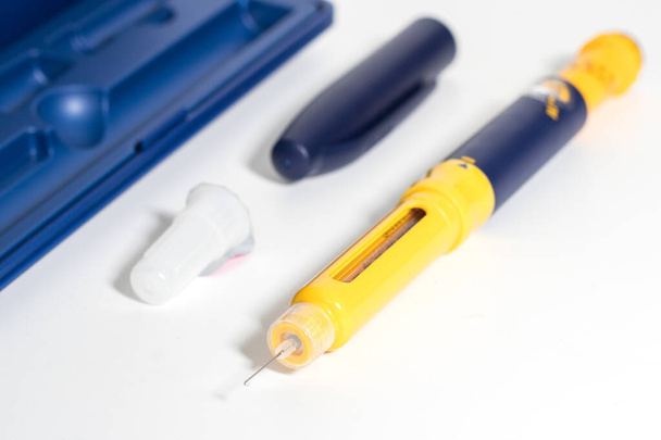 Инсулиновая ручка с каплей инсулина на кончике иглы изолирована на белом фоне. Медицинские приборы используются для самостоятельной инъекции при лечении диабета. Всемирный день диабета и концепция здравоохранения. - Фото, изображение