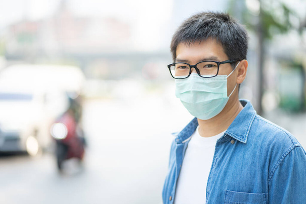 HandsomeMan wearing face mask protect filter against air pollution (PM2.5) or wear N95 mask. protect pollution, anti smog and Covid 19 viruses, Air pollution caused health problem. Global warming. - Valokuva, kuva