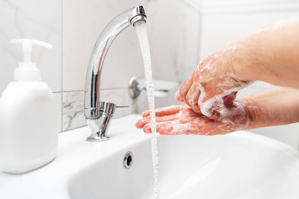 個人の衛生、ウイルスから保護するために頻繁に蛇口に石鹸で手を掃除します。. - 写真・画像
