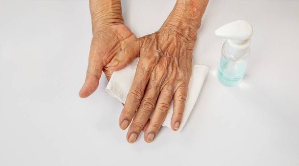 Idős nő, aki alkoholos géllel tisztítja a kezét, hogy védekezzen a coronavirus covid-19 ellen - Fotó, kép