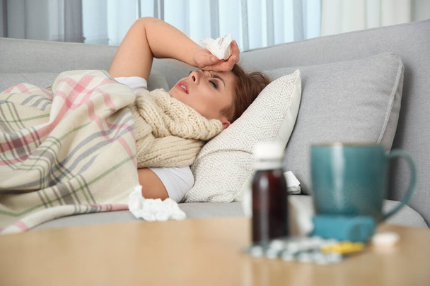Sick woman lying on sofa at home. Influenza virus - Foto, imagen