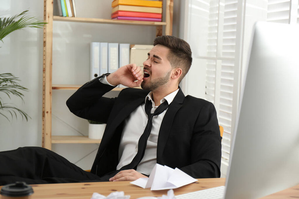 Lazy employee yawning at table in office - Фото, изображение