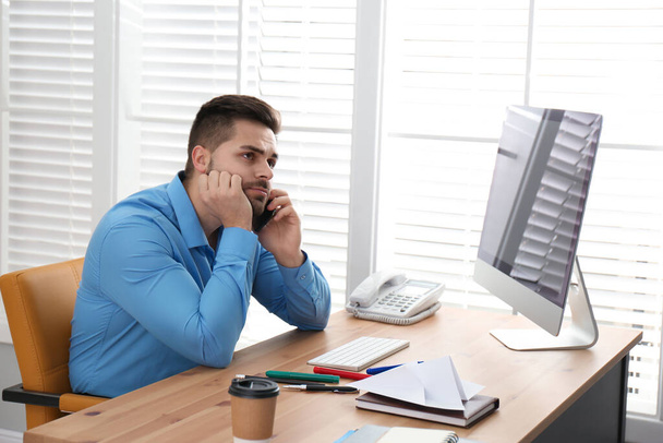 Fauler Mitarbeiter telefoniert am Tisch im Büro mit dem Smartphone - Foto, Bild