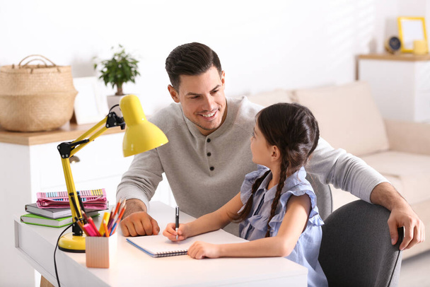 Man helping his daughter with homework at table indoors - Photo, Image