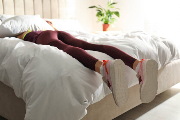 Lazy young woman sleeping on bed instead of morning training, focus on legs - Foto, Imagem