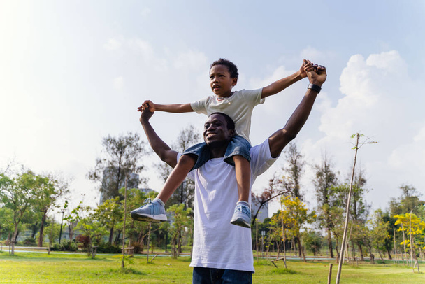 Χαρούμενος Αφρο-Αμερικανός πατέρας και γιος στο υπαίθριο πάρκο. Οικογενειακή δραστηριότητα Σαββατοκύριακο - Φωτογραφία, εικόνα