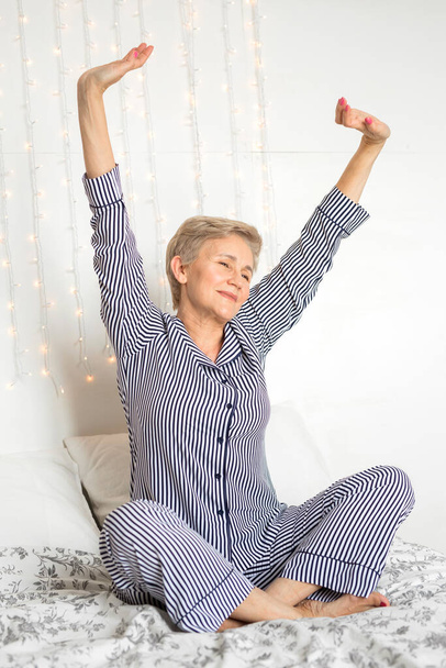  beautiful elderly woman in pajamas on the bed - Photo, Image