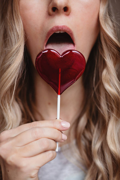Beautiful young woman with sweet lollipop red color - Photo, Image