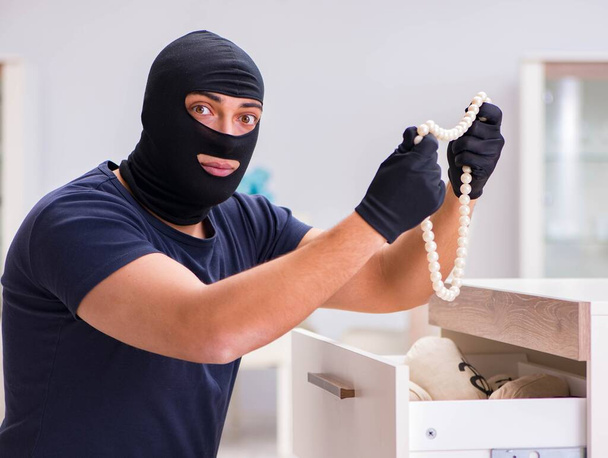 Un voleur portant de la cagoule vole des objets de valeur - Photo, image