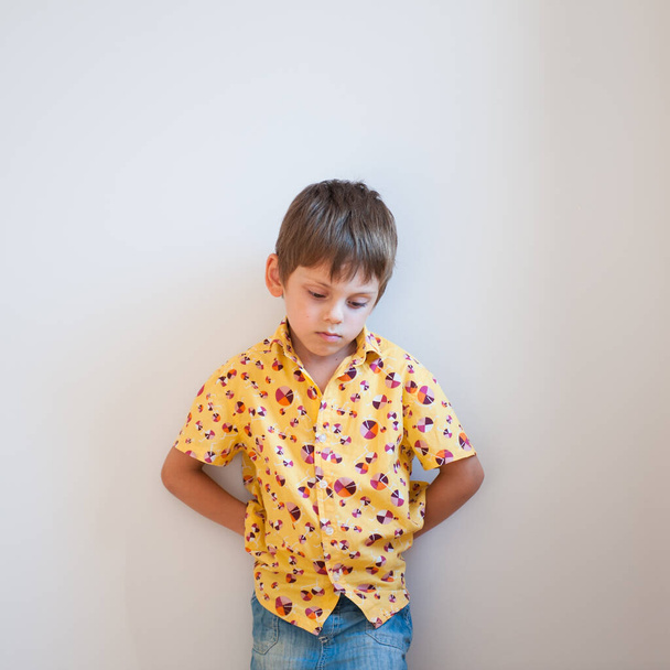 stress mind state concept on upset little kid in shirt head down leaning wall - Fotoğraf, Görsel