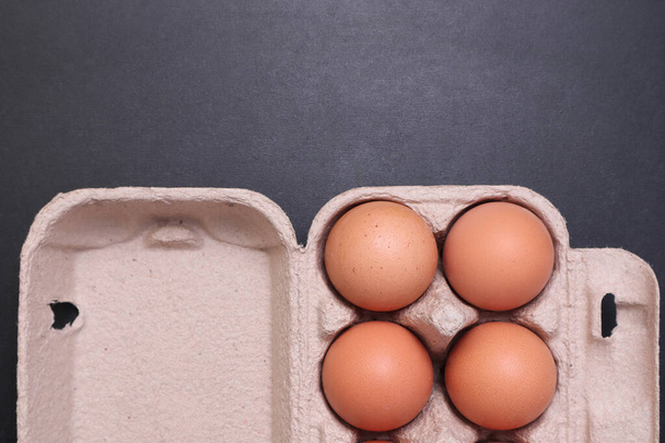 Chicken eggs in a paper box on a black textured background. - Foto, imagen