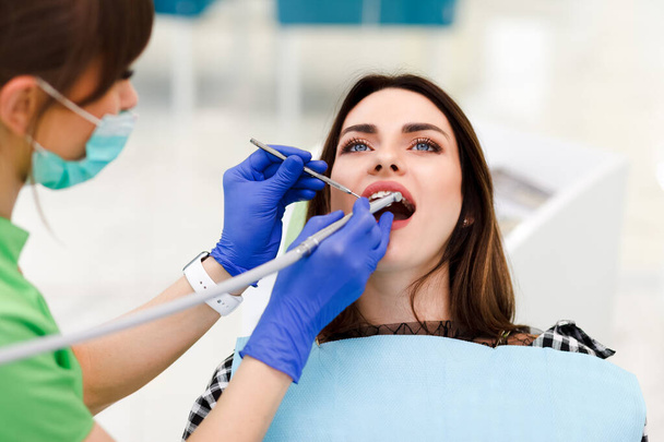 A fogorvos fúróval fúrja a fogait egy fiatal nőnek. Lány a fogorvosnál. - Fotó, kép