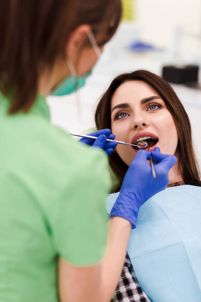 Der Zahnarzt macht eine mündliche Untersuchung. Hübsche Patientin kam zum Zahnarzttermin - Foto, Bild