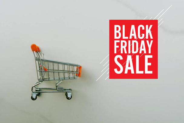 Shopping cart on marble white floor texture background with black friday sale graphic design.  - Photo, Image