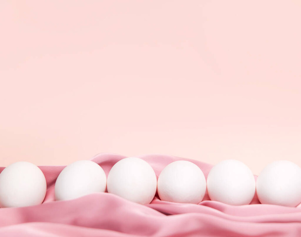 Δημιουργικό πασχαλινό μπεζ και ροζ φόντο με λευκά αυγά. Πάσχα διακοπές ελάχιστη έννοια. - Φωτογραφία, εικόνα