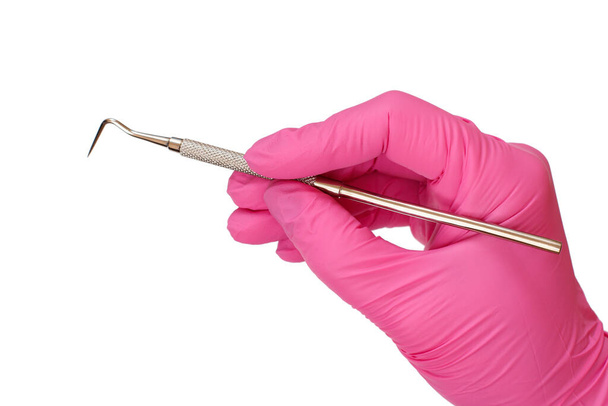 Vista de cerca de la mano del dentista en guante de látex rosa con sonda sobre fondo blanco aislado. Concepto de herramientas médicas
. - Foto, Imagen