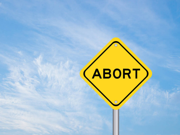 Желтый транспортный знак со словом аборт на голубом фоне неба
 - Фото, изображение