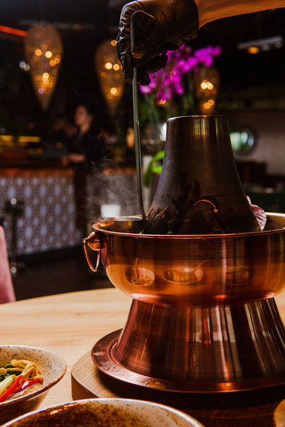 rajattu laukaus ihmisen käsi käsine tilalla kauha ja ruoanlaitto perinteinen aasialainen hot pot ateria
 - Valokuva, kuva
