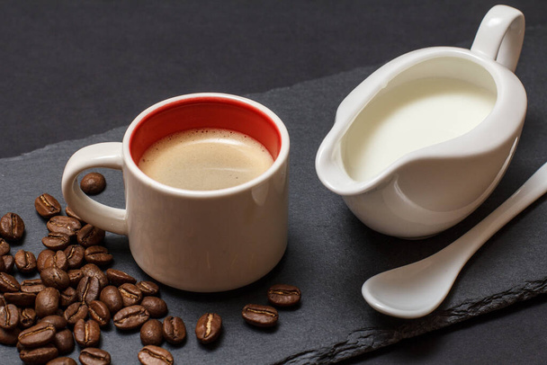 Cup of coffee, coffee beans, spoon and jug of cream on black background. Top view. - Foto, immagini