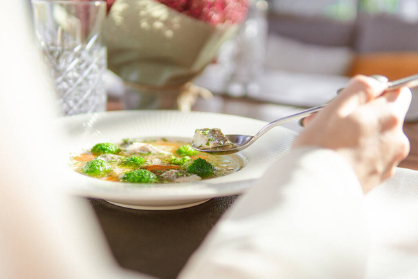 close-up partial view of woman eating delicious healthy soup with vegetables in restaurant - Photo, image