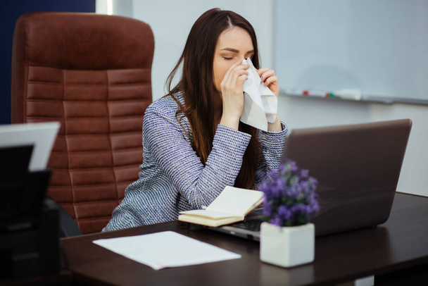 Jonge zieke vrouw huilen of met allergie, afvegen ogen met weefsels tijdens het werken met de laptop in office. Slecht nieuws op werken, ontslagen werknemer concept - Foto, afbeelding
