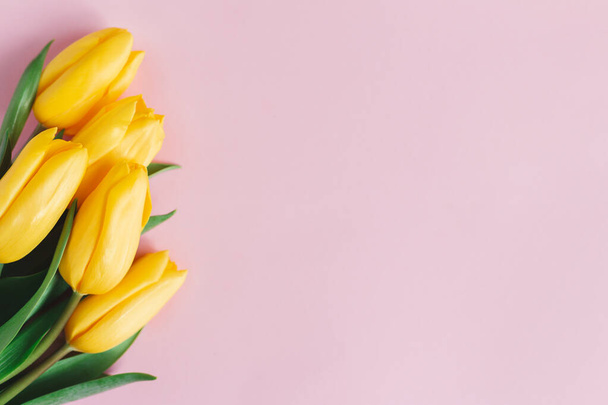 Tender tulipanes amarillos sobre fondo rosa pastel. Tarjeta de felicitación para el día de la madre. Acostado. Lugar para el texto.  - Foto, imagen
